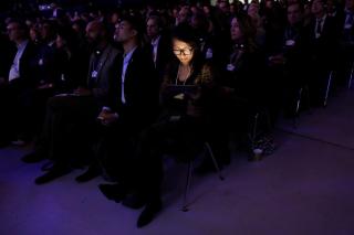 Una mujer iluminada con la luz de su teléfono, en un auditorio.