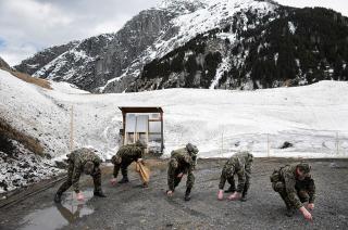 Imagen de invierno :Soldados inclinados recogen casquillos. Al fondo una montaña