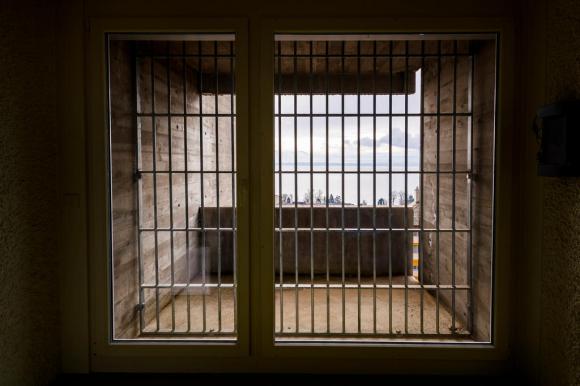 Blick durch ein Fenster einer Gefängniszelle mit Blick auf einen See.