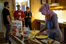 asilantes en la cocina de un centro de acogida: una mujer cocina y tres hombres platican