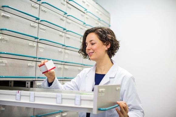 Angestellte in einer Apotheke vor riesigem weissem Medikamentenschrank mit Schubladen