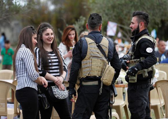 Dos muchachas hablan con dos milicianos.
