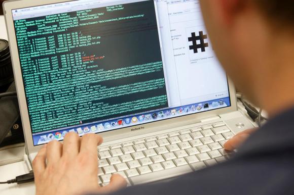 Datenlawine auf Bildschirm vor einem User, von dem nur die linke Hand und ein kleiner Teil des Kopfs zu sehen sind.