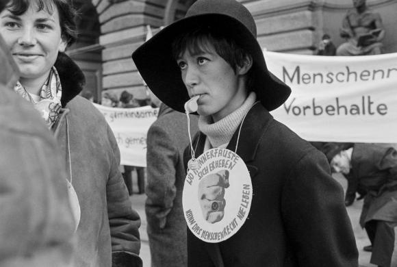 Frau mit Trillerpfeife und Schlapphut an einer Demonstration, Schwarzweiss