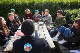 Jugendliche debattieren an einem Tisch zum Thema Klimaschutz