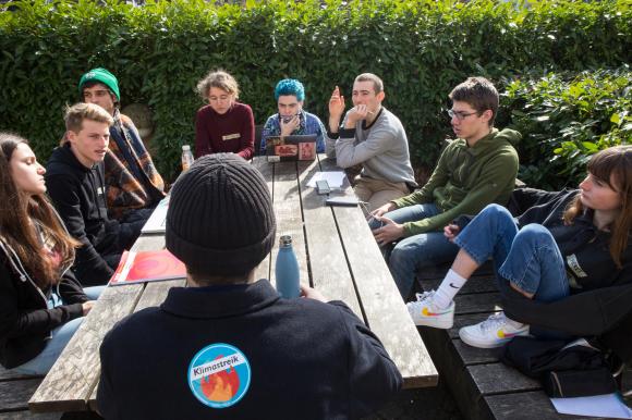 Jugendliche debattieren an einem Tisch zum Thema Klimaschutz