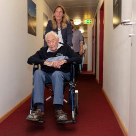 Un hombre mayor en una silla de ruedas empujada por una mujer