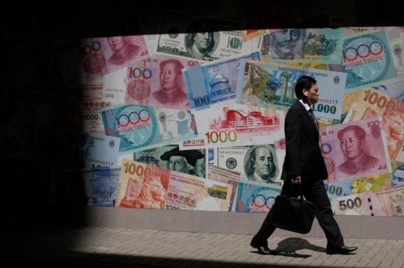 様々な紙幣の壁画の前を歩くビジネスマン