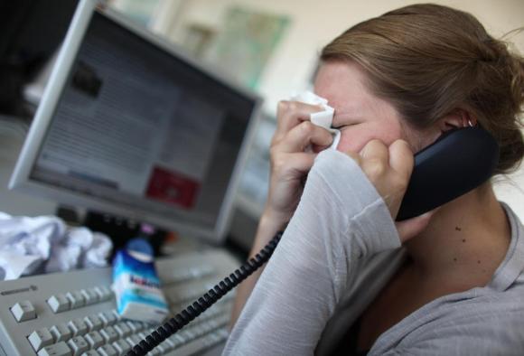 Une femme pleurent devant son écran d ordinateur, un téléphone à la main