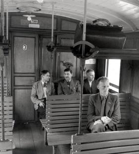 Antigua imagen de viajeros en tercera clase en el tren con asientos de madera.