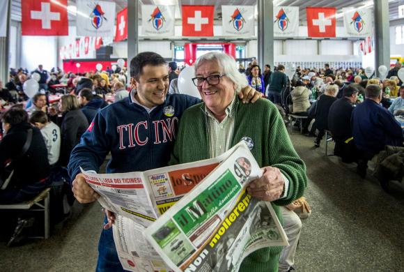Deux hommes lisent un journal au milieu d une assemblée.
