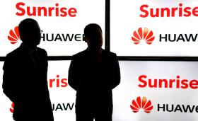 two dark figures against Sunrise Huawei posters
