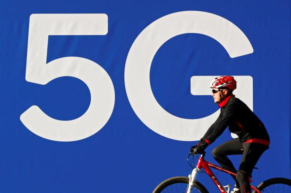 Un ciclista passa davanti a una parete con la scritta 5G