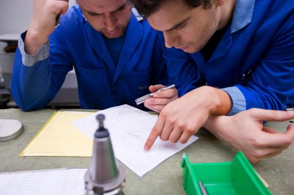 zwei Mitarbeiter des Werkzeugherstellers Urma AG studieren ein Dokument auf dem Arbeitstisch.