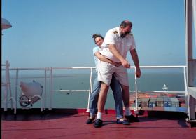 Mulher tenta carregar homem grande no deck dum navio