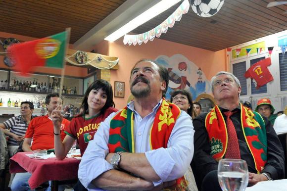 Pessoas assistindo uma partida de futebol na televisão