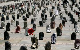 A lone flower is propped up by a boot at a shoe installation marking International Day for Landmine Awareness