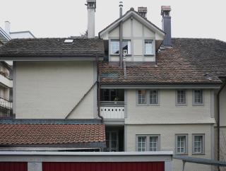 Eine Katzenleiter führt von einem Dach über ein anderes Dach zu einem Fenster.