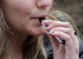 Una chica fuma un cigarrillo electrónico