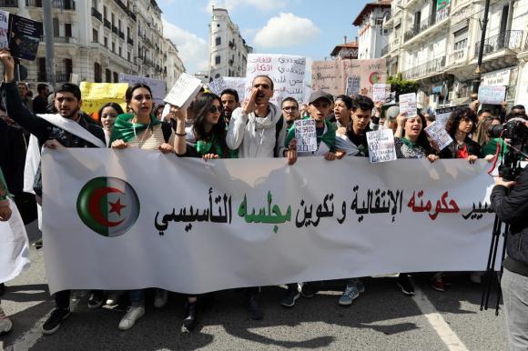 متظاهرون شبان يرفعون لافتة في شارع وسط الجزتئر العاصمة