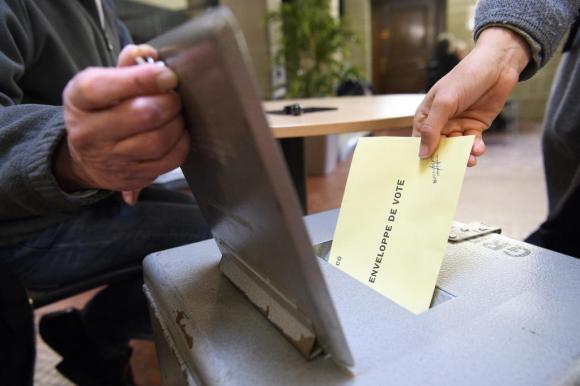 Une urne de vote avec quelqu un qui glisse son bulletin dedans