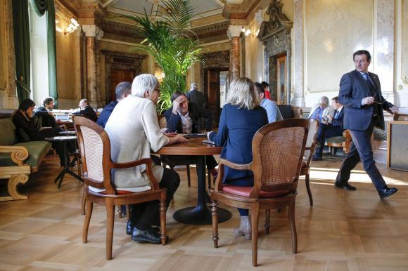 Mitglieder des Schweizer Parlaments sitzen in der Vorhalle an einem Tisch und besprechen sich