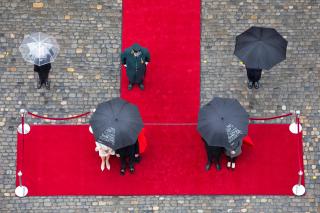 赤じゅうたんと傘をさす人々を上からみた写真