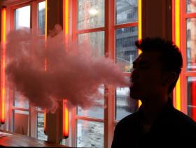 man exhales vapor from an e-cigarette