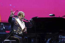 Elton John al piano y hablando ante un micrófono