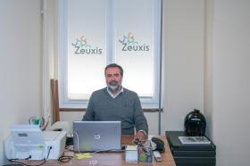 Ein Mann in einem Büro, am Fenster der Schriftzug Zeuxis