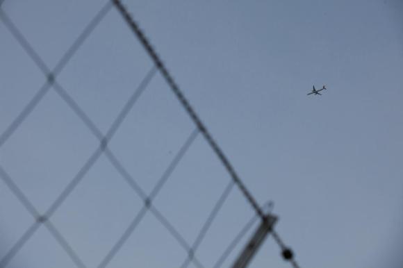 Imagen de un fragmento de valla y un avión en vuelo