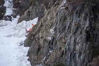 Eine Felswand und ein Schneekorridor am Berg