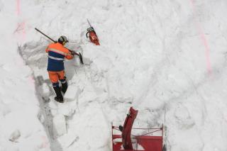 Un homme pelle la neige sur un énorme tas de neige