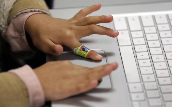 Las manitas de un niño en un teclado de computadora.