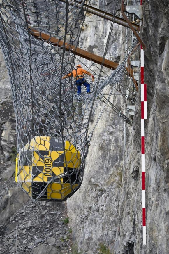 Man-made boulder catches in rock protection fencing on a mountainside