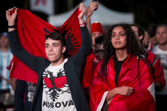 ragazzo con la bandiera albanese e ragazza avvolta in una bandiera svizzera