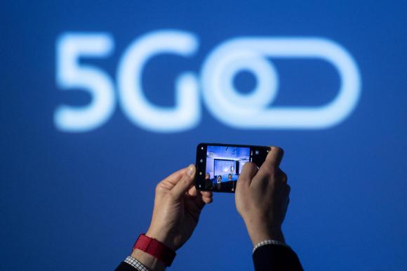 phone being held up in front of a 5G publicity banner
