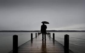 傘をさして桟橋に立つ男性