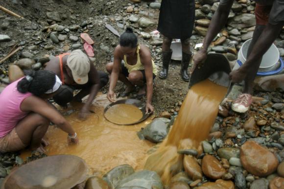 Women pan for gold along the Dagua River in Zaragoza, Colombia