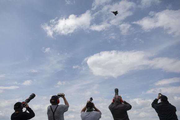 مجموعة من الأشخاص يلتقطون صوراً لطائرة مقاتلة من طراز رافال