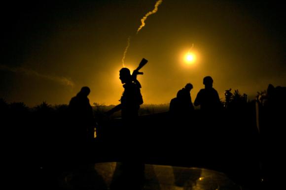 A US-backed Syrian Democratic Forces (SDF) fighter watches illumination rounds light up Baghouz, Syria, in March, 2019