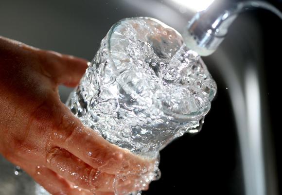 Main en train de remplir un verre d eau sous un robinet.