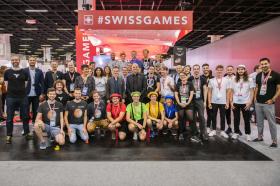 在科隆国际游戏展上，阿兰·贝尔赛站在绿色上衣的男士身后，与瑞士文化基金会会长菲利普·比朔夫(Philippe Bischof)和瑞士游戏业代表团合影。