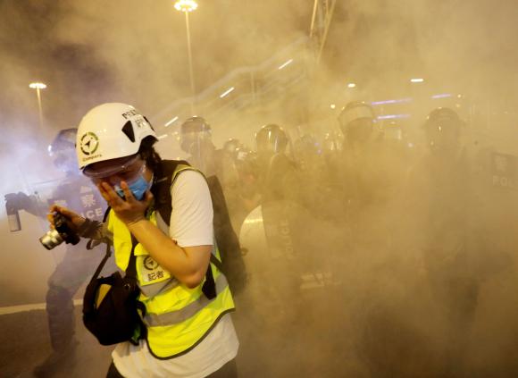 一名女記者在香港街頭受到了催淚彈的驅趕。
