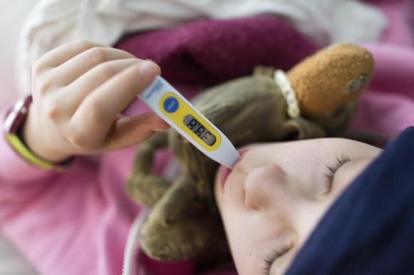 Child with a thermometer, measuring a fever