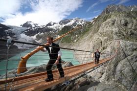 Dos hombres caminan sobre un puente colgante de montaña.