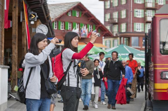 Two Asian tourists taking a picture in Swiss mountain resort
