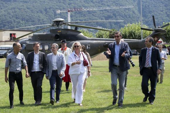 Un grupo de políticos camina en el pasto. Detrás hay un helicóptero.