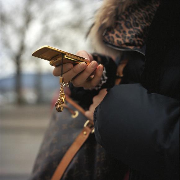 Mujer de espaldas con un teléfono móvil dorado