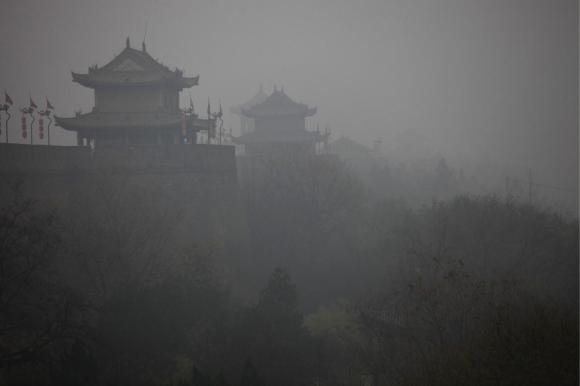 Ein grauer Dunst, Smog, liegt über einer alten chinesischen Stadtmauer.